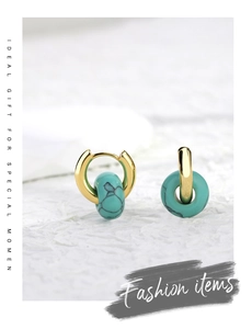 Detailed close-up of retro golden hoop earrings with synthetic turquoise stone texture