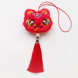 Détail du pendentif de danse du lion en peluche rouge avec pompons en soie et perle blanche
