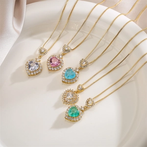 Macro detail of five double-layer gold heart necklaces with colorful micro-pave crystals