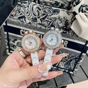 Detail of luxury ceramic watches with diamond bezels in gold and silver held by hand