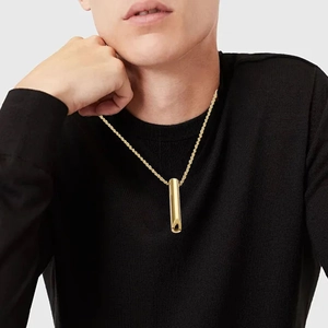 Dettaglio di una collana a fischietto d'oro su maglione nero con catena a cordoncino
