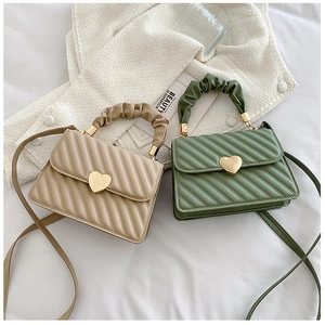Close-up of beige and green quilted handbags with heart locks and ruched handles