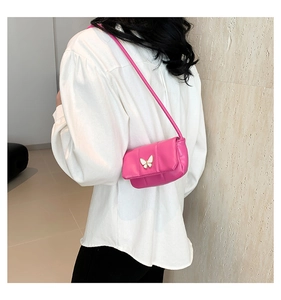 Détail d'un sac à bandoulière rose matelassé avec fermoir papillon blanc et rabat élégant