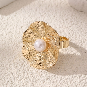 Detail of vintage golden hammered ring featuring a large wave disk with a center pearl