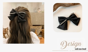 Details einer schwarzen Satin-Haarklammer mit doppelter Schleife und eleganten Perlen