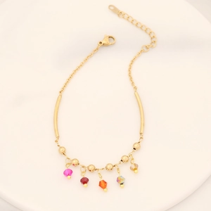 Bracelet chaîne dorée avec pampilles en cristal coloré sur un plateau blanc élégant