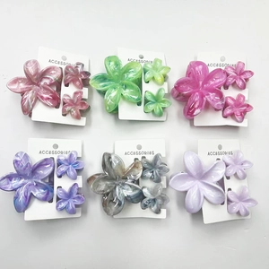 Flat lay of frangipani flower hair claw sets in marble texture and six vibrant colors