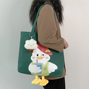Detail of green canvas tote bag featuring a cartoon duck and plush cloud pendant
