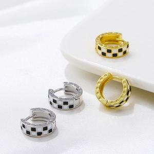 Gold and silver checkerboard hoop earrings with star engravings on silk background