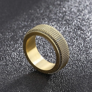 Macro view of golden spinner ring showing woven mesh texture and polished steel inner band