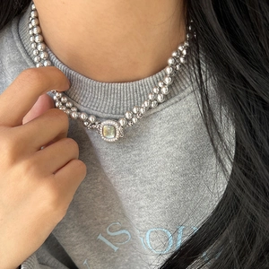 Detail of double-layer pearl necklace with geometric opal pendant worn on model