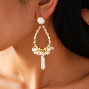 Detailed close-up of Baroque teardrop pearl earrings in gold setting worn by model