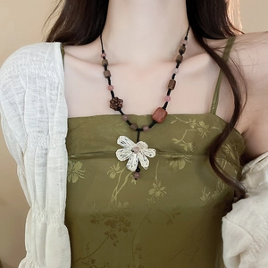 Detail of bohemian woven necklace with brown beads and white flower pendant on model