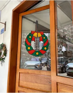 Détail d'un sticker de fenêtre couronne de Noël avec nœud rouge et cloches dorées