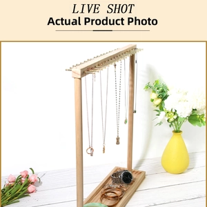 Detail of wooden jewelry display stand with metal hooks and base tray on white tabletop