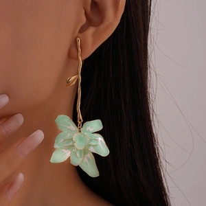 Close-up of green drip oil flower earrings on model featuring elegant golden stems