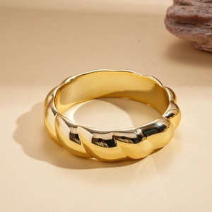 Macro shot of wide golden metal bracelet featuring unique twisted geometric texture details