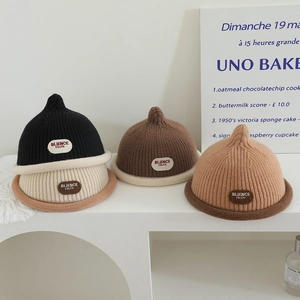 Knitted pointed beanie for kids in black, cream, and brown with soft ribbed texture