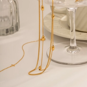 Détail du collier double couche plaqué or 18k avec perles ovales et pendentif croix
