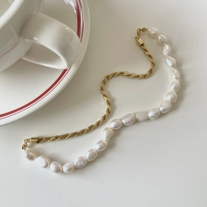 Baroque pearl and gold twisted rope necklace on a minimalist white surface