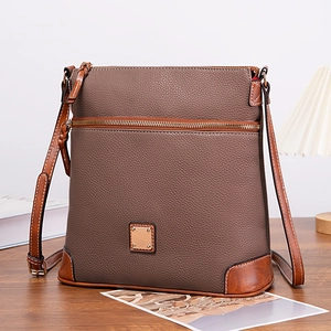Close-up of brown pebbled leather Boston crossbody bag with contrast stitching and metal plate
