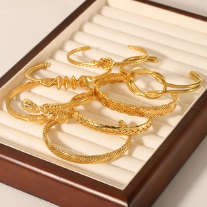 Set of 18K gold plated stainless steel knot bracelets and twisted bangles on a tray