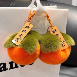 Dettaglio portachiavi in peluche a forma di cachi arancione con ciondolo in acrilico