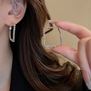 Macro shot of silver textured geometric square hoop earrings showing metallic details