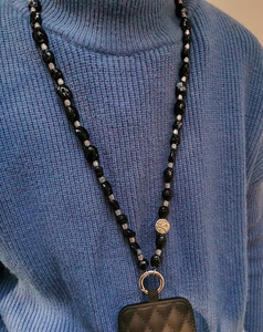 Detail view of ethnic black faux turquoise beads and gold coin charm on phone strap