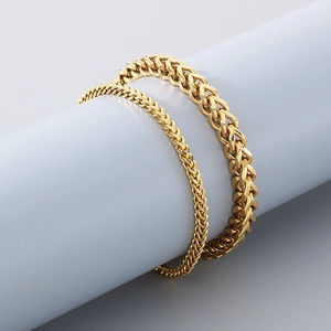 Macro shot of two different widths of golden wheat chain bracelets on a display stand