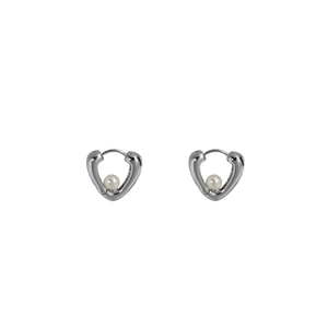 Détails macro des boucles d'oreilles cœur argenté ornées d'une perle ronde blanche lisse