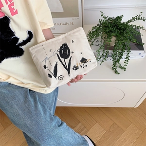 Close-up of canvas makeup bag featuring floral tulip embroidery and artistic lettering