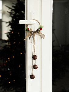 Christmas door hanger with bronze bells, plaid bow, and red berries on a door handle