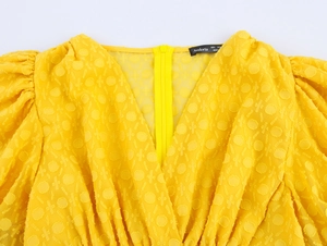 Detail des gelben V-Ausschnitts mit Reißverschluss und gepunktetem Stoff am Kleid