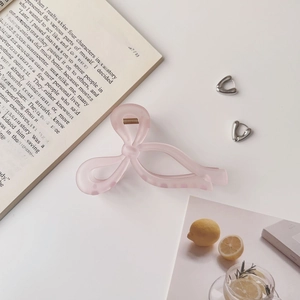 Détail d'une grande pince à cheveux rose avec nœud élégant et finition mate douce