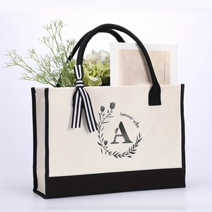 Detail of canvas tote bag featuring floral letter A print and striped ribbon accent