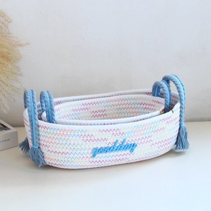 Detail of woven cotton rope storage baskets with blue handles and goodday embroidery