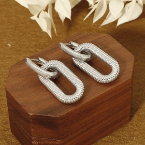 Detail of silver double-loop earrings with threaded texture on wooden hexagonal stand