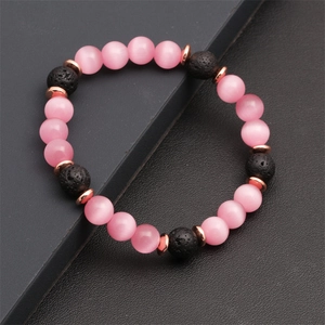 Dettaglio di perline rosa occhio di gatto e pietre laviche nere su bracciale elastico