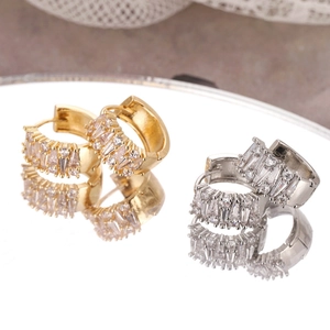 Elegant gold and silver hoop earrings with cubic zirconia stones on mirror surface