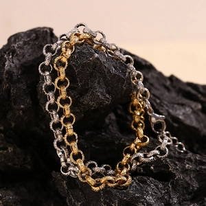 Macro detail of 14K gold and silver wheat pattern link chain bracelet on volcanic rock