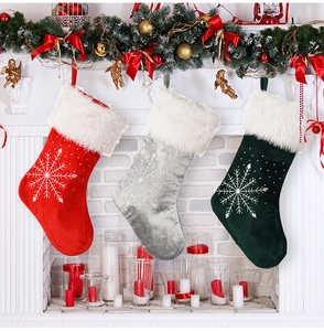 Trois chaussettes de Noël brodées avec flocon de neige sur une cheminée festive décorée