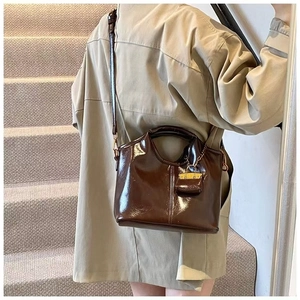 Detailed close-up of dark brown wax leather tote with golden hardware and mini pouch