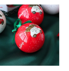 Close-up of red and white Christmas baubles featuring a holiday car design and silk ribbons