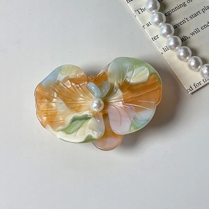 Close-up of a colorful acetate orchid hair clip with a pearl center on a white background