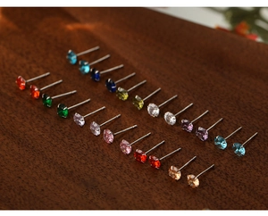 Macro shot of assorted colorful round zircon earrings on a rustic wood background