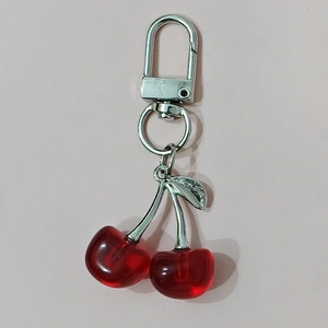 Red resin crystal cherry keychain with silver alloy leaf and lobster clasp on pink background