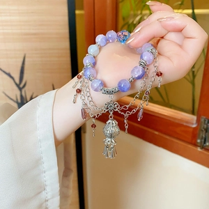 Macro detail of Chinese style beaded bracelet with silver lantern pendant and purple beads
