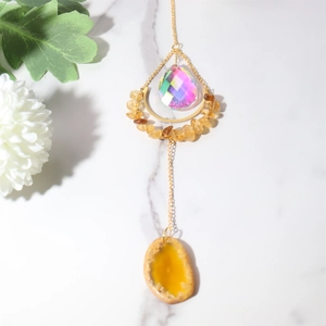 Macro view of crystal suncatcher featuring yellow agate slice and golden crescent moon