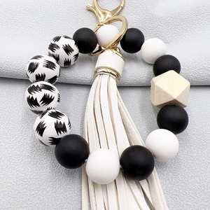 Detail of beaded keychain with black white silicone beads, wooden bead, and white PU tassel